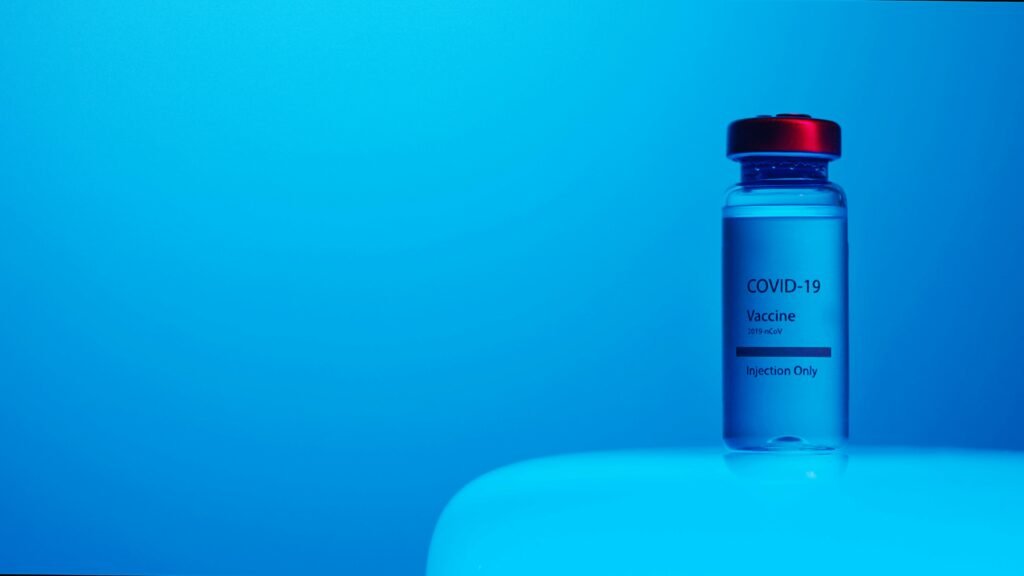 A COVID-19 vaccine vial with clear labeling on a serene blue background, symbolizing hope and health.